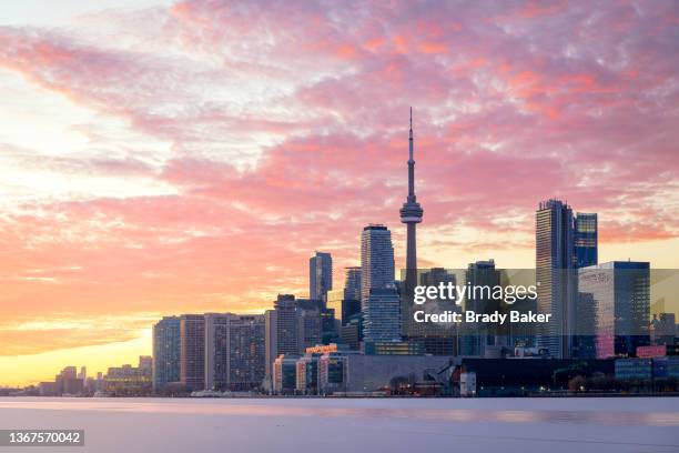 toronto skyline and colorful sunset with frozen lake ontario - toronto photos et images de collection