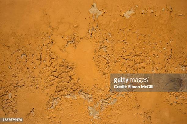 peeling and faded paint on a stucco and adobe building exterior wall - uneben stock-fotos und bilder