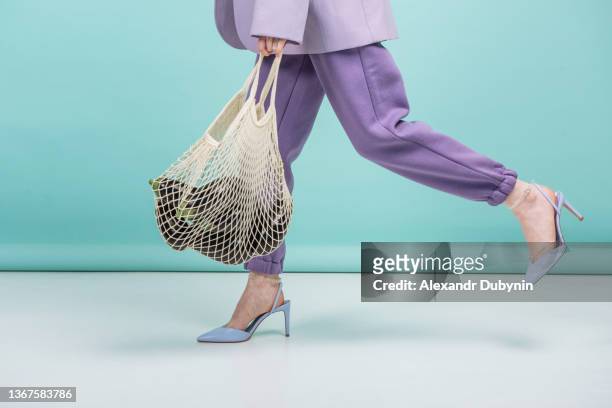 beautiful female legs in shoes with a mesh bag with eggplant go. - lila schuhe stock-fotos und bilder