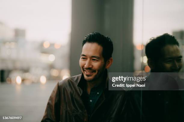 cheerful man in city at dusk - レザージャケット ストックフォトと画像