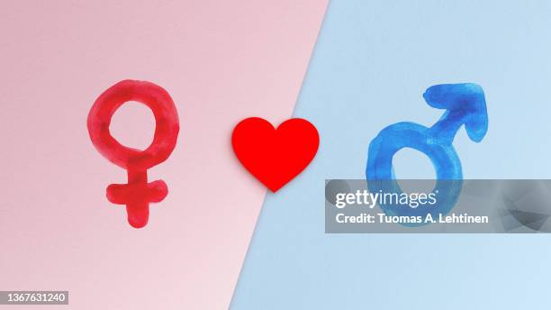 red female gender symbol, heart and blue male gender symbol on light pink and blue papers. - gender symbol stock pictures, royalty-free photos & images