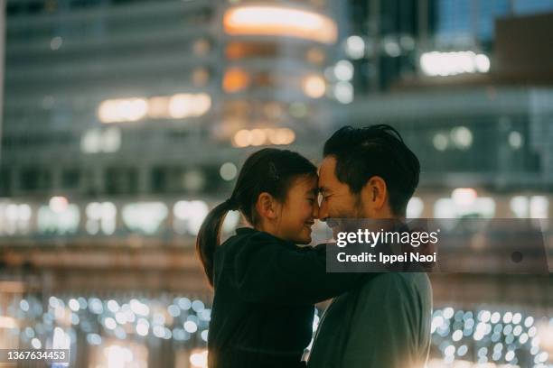 father and young daughter embracing at night in city, tokyo - center street elementary stock pictures, royalty-free photos & images