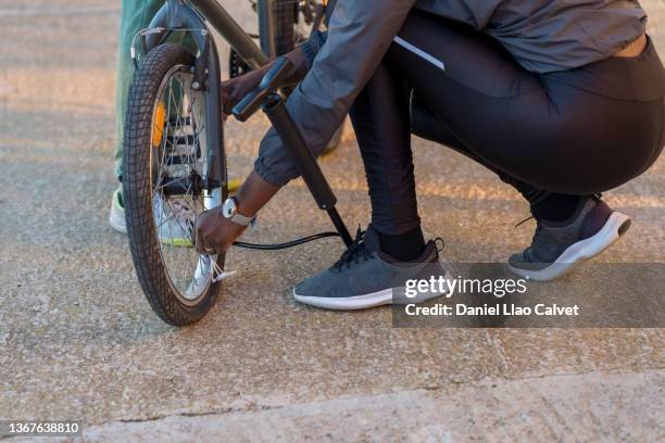 close-up of an unrecognizable woman preparing the air pump to inflate her son's bicycle tire - familie fietsen close up stockfoto's en -beelden
