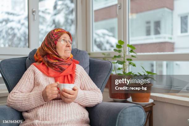 porträt einer muslimischen frau, die sich zu hause entspannt - arab old woman stock-fotos und bilder