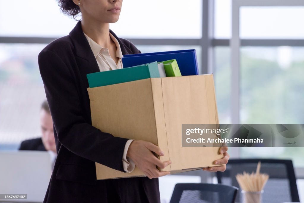Business concept : An unemployed with her cardboard box walking out of the office
