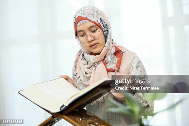 the quran: the holy book of islam. muslim women is reading the koran in prayer room at her home. - namaz stock pictures, royalty-free photos & images