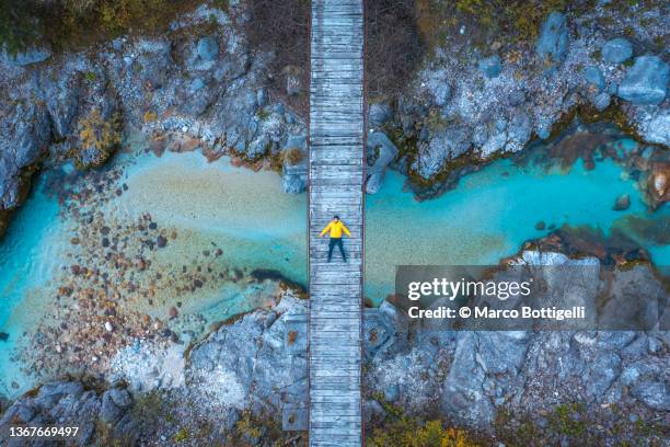 aerial view of person lying on a wooden bridge above a turquoise river - central fotografías e imágenes de stock