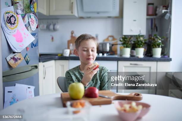cute boy taking a huge bite of a red apple - mâchonné photos et images de collection