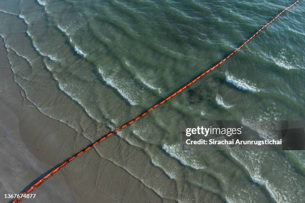 Small amount of oil is dispersed by the waves near a boom that is deployed to control the oil spill on January 30, 2022 in Rayong, Thailand....