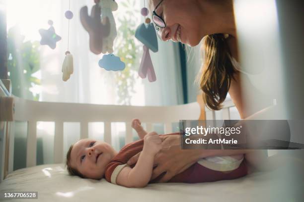 mother with her cute baby girl in her crib - babysäng bildbanksfoton och bilder