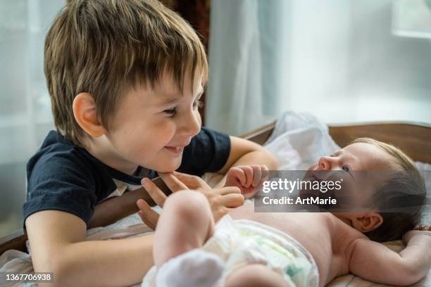 彼のかわいい赤ちゃんの妹を満たす小さな男の子 - 兄弟 ストックフォトと画像