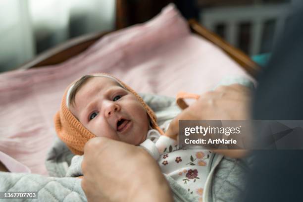 vater setzt hut auf sein süßes mädchen - baby mütze anziehen stock-fotos und bilder