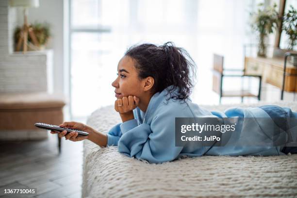 giovane donna africana che guarda la tv a casa - guardare la tv foto e immagini stock