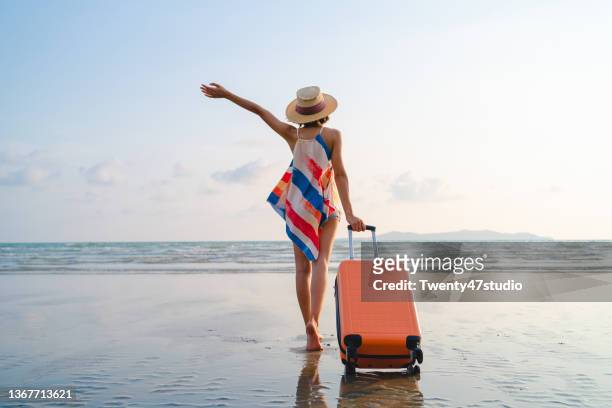happy asian woman with sunhat enjoy travel on the beach in summer - holiday suitcase stockfoto's en -beelden