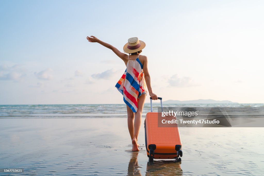 Happy Asian woman with sunhat enjoy travel on the beach in summer