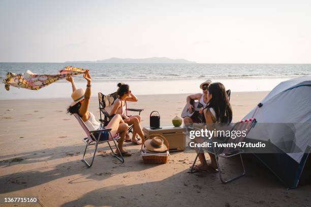 group of asian friends having fun enjoying beach camping in summer - convivio imagens e fotografias de stock