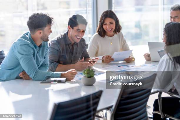 multi racial diverse group of people working with paperwork on a board room table - report fun stock pictures, royalty-free photos & images