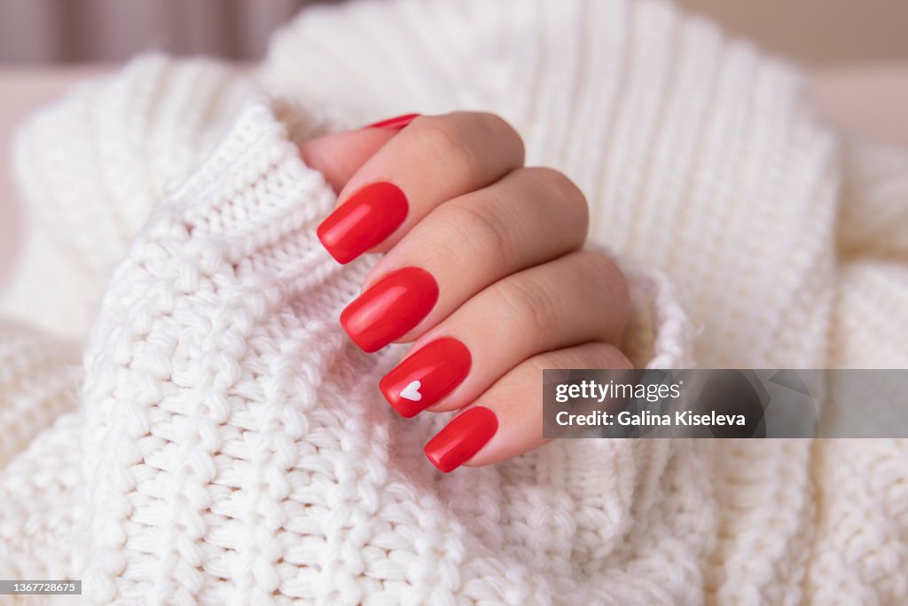 Female hand with red manicure nails, hearts design