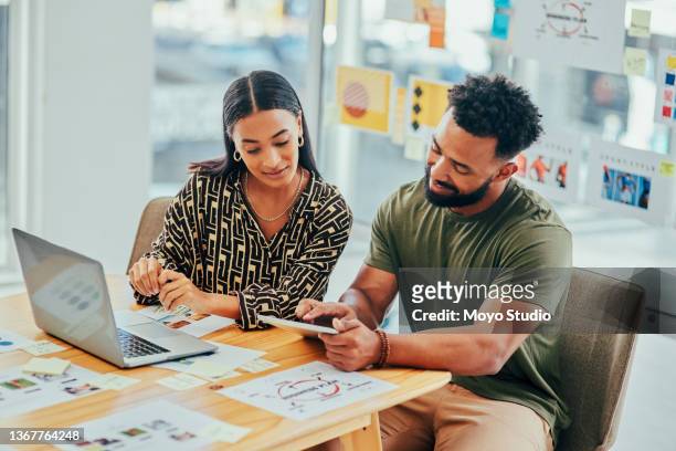 photo de deux jeunes designers travaillant sur un ordinateur portable et une tablette numérique dans un bureau - publicité photos et images de collection