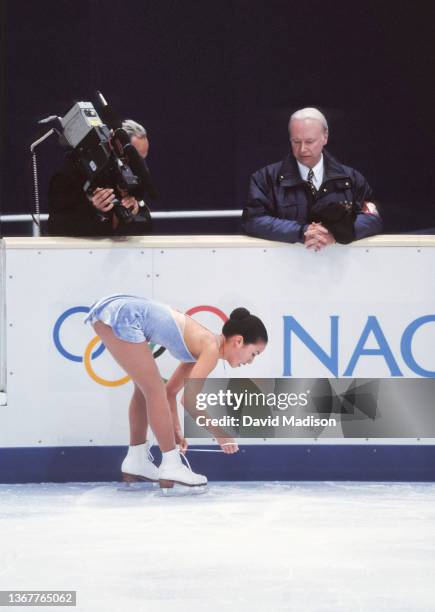 Michelle Kwan of the USA ties her skate lace as her coach Frank Carroll looks on before the start of her free program in the Ladies Singles event of...