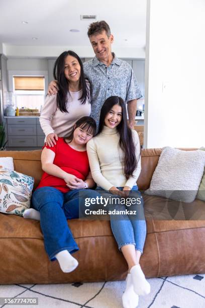 diverse family sitting together on the couch at home. one daughter has down's syndrome. - adopted chinese daughter stock pictures, royalty-free photos & images