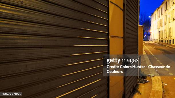 rolling garage door and empty street in paris at night - industrial door stock pictures, royalty-free photos & images