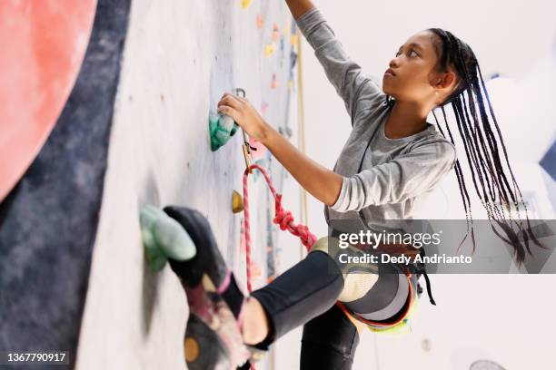 cool indonesian teenage rock climber athlete climbing wall - climbers stockfoto's en -beelden