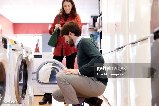 a couple chooses a new washing machine. - new guidance stock pictures, royalty-free photos & images