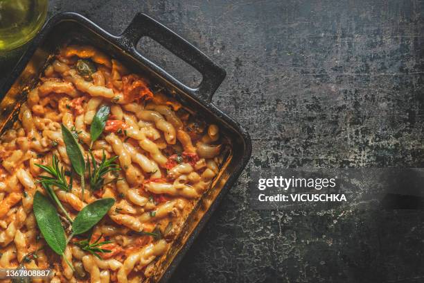 homemade italian noodles with tomato sauce, rosmary and sage in black casserole at rustic dark concrete kitchen table - sage stock pictures, royalty-free photos & images