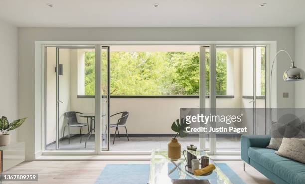stylish show home living room of a contemporary apartment with open sliding doors onto a balcony - living room window stock-fotos und bilder