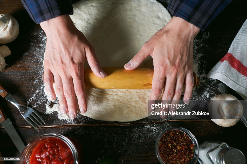 Cooking Italian Vegetarian Pizza With Vegetables And Mushrooms At Home, On A Wooden Table. The woman Kneads and Rolls the Dough with her hands. Step-by-step instructions, Do it Yourself. Step 1.