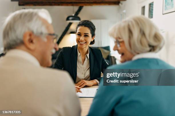 senior couple consults with female real estate  agent - 財經顧問 個照片及圖片檔