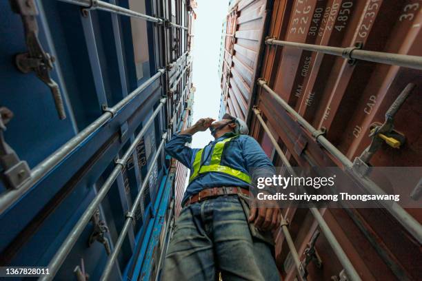 young man engineer working in container cargo warehouse at terminal commercial port for business logistics, import export or freight transportation. - dockers stockfoto's en -beelden