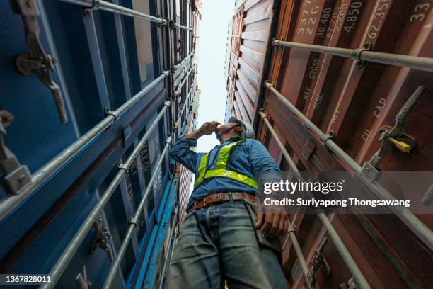 young man engineer working in container cargo warehouse at terminal commercial port for business logistics, import export or freight transportation. - low angle stock pictures, royalty-free photos & images
