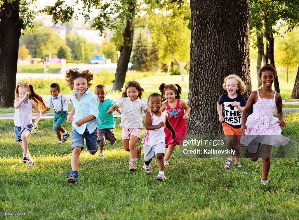 A group of preschoolers running on the grass in the Park