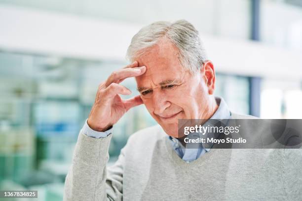 shot of a senior man suffering from a headache at a clinic - dementie stockfoto's en -beelden
