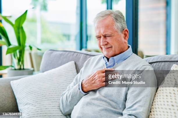 aufnahme eines älteren mannes, der in einer klinik schmerzend die brust hält - chest pain stock-fotos und bilder