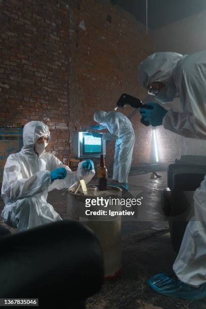 criminologists in protective suits picturing physical evidences at the crime scene - criminology stock pictures, royalty-free photos & images