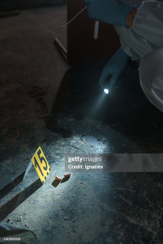Criminologists lighting two bullets on the floor with flash light