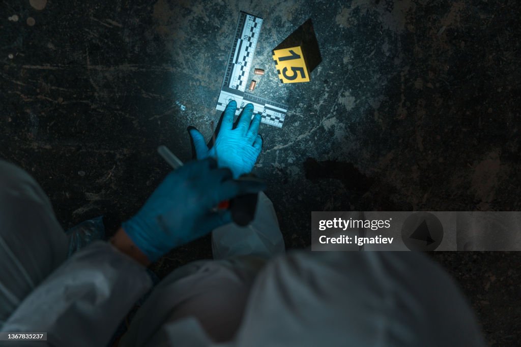 Picture of physical evidence on the floor, with a crime scene number and two bullets