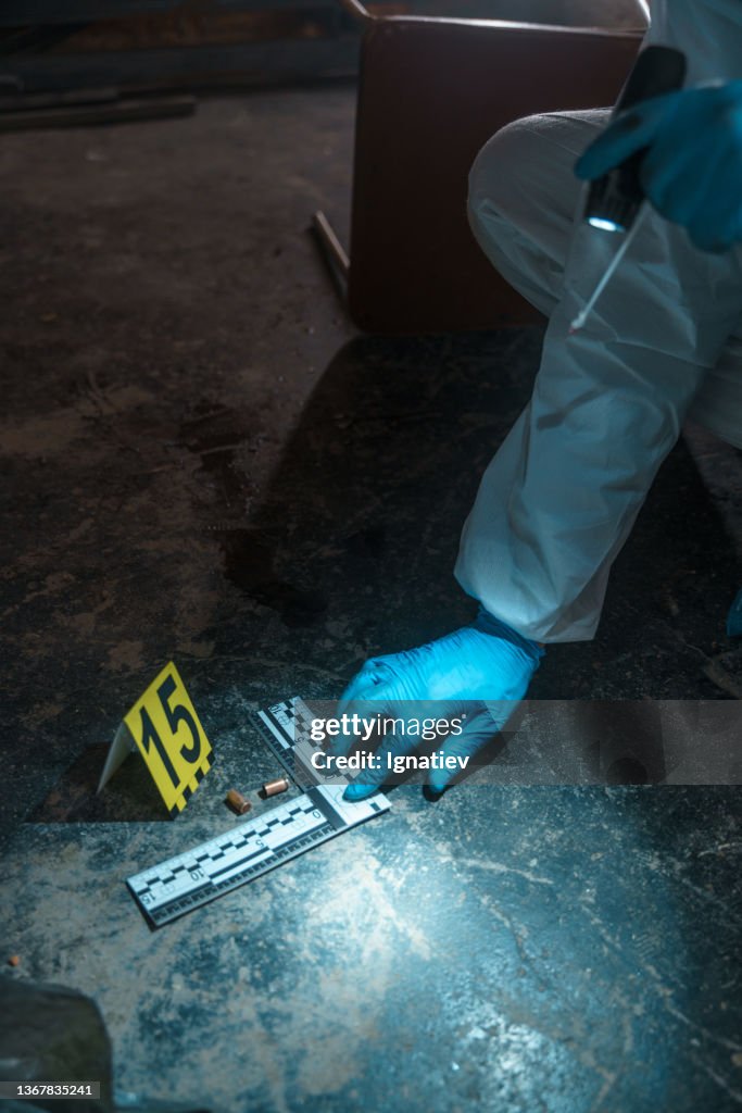 Crime scene number on the floor near two bullets, measuring by a special ruler of criminologists