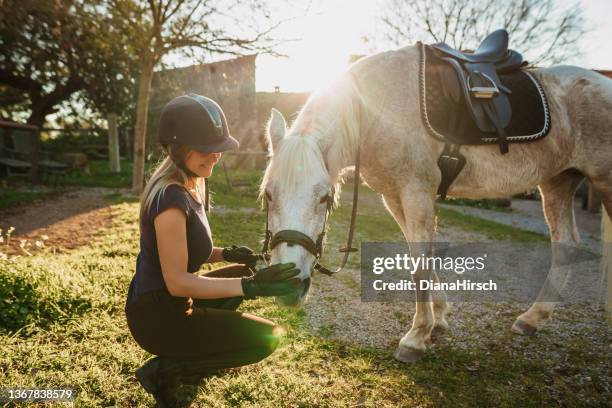 beautiful blond woman enjoying her horse after riding training at a rustic stable outdoors in majorca - riding habit stock pictures, royalty-free photos & images