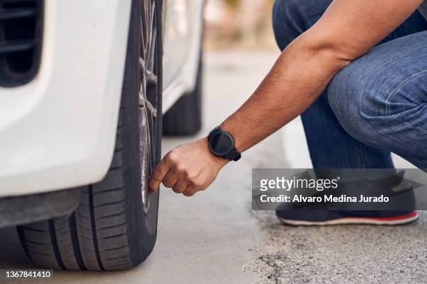 close-up of unrecognizable man checking the status of his car's tires. concept of driving and driving safety. - band stockfoto's en -beelden