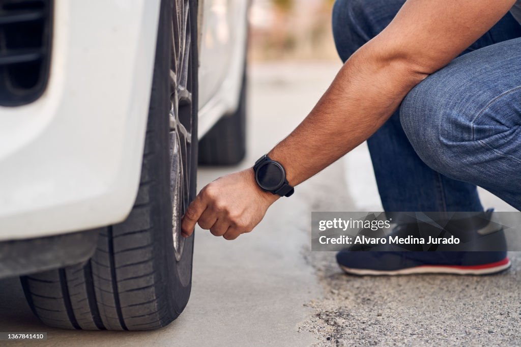Close-up of unrecognizable man checking the status of his car's tires. Concept of driving and driving safety.