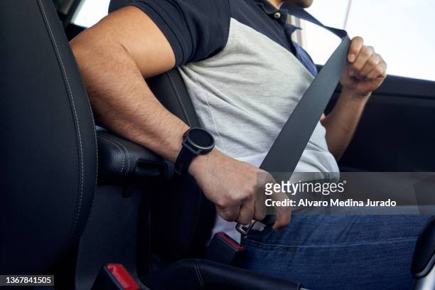 unrecognizable young hispanic man buckling his seat belt inside his car. - seat belt stock-fotos und bilder
