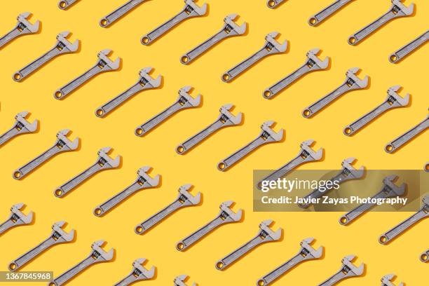 many adjustable wrenches on yellow background - werkzeug stock-fotos und bilder