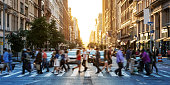 Crowds of people walking across a busy crosswalk at the intersection of 23rd Street and 5th Avenue in Manhattan New York City