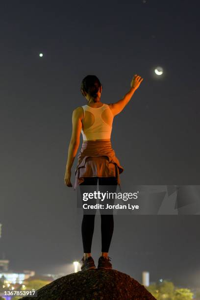 woman with arms raised reaching for the moon - arms raised foto e immagini stock