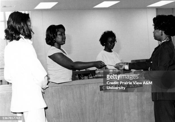 African American women at the circulation desk in the W.R. Banks Library at Prairie View A&M University, Prairie View, TX, 1970s.
