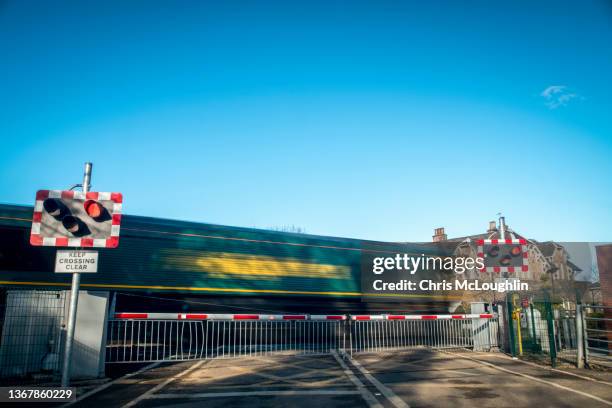 a level crossing with a passing goods train leaving drax power station - level crossing stock pictures, royalty-free photos & images
